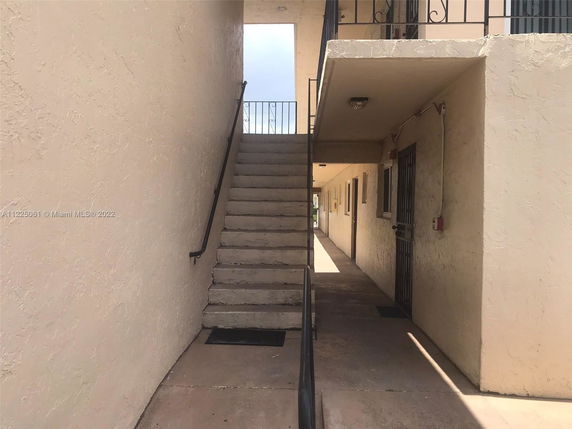 Exterior view of a stairway in a multi-story building with beige walls and metal railings.