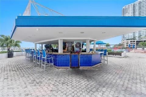 Outdoor bar area with blue seating and surrounding high-rise buildings.