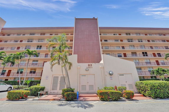 Front view of a multi-story apartment building with balconies.