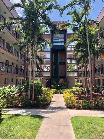 Front view of a multi-story building with balconies and an exterior elevator.