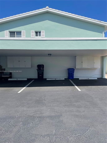 Outdoor covered parking area with two parking spaces in front of a building.