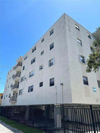 Front view of a multi-story apartment building with balconies and black fencing.