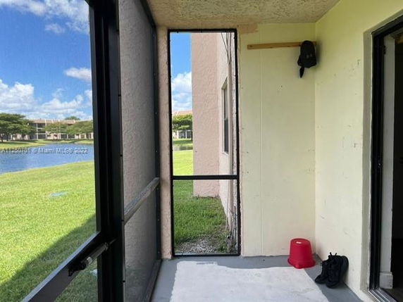 View of a grassy area and a pond seen from a screened balcony.