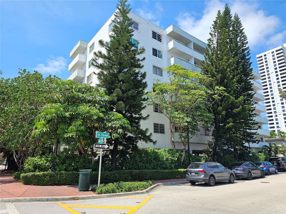 Front view of a multi-story white building with balconies.