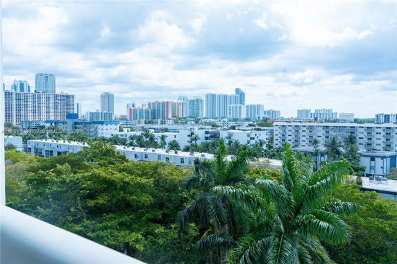 Panoramic urban view with multiple high-rise buildings and greenery in the foreground.