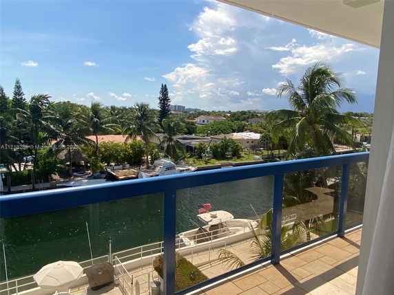 Panoramic view from a balcony overlooking a canal with boats and surrounding palm trees.