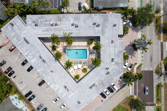 Aerial view of a building rooftop with central swimming pool and surrounding parking area.