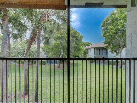 View from a balcony showing trees, grass, and another building in the distance.