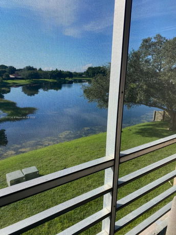 View of a lake and trees seen from a building through a screened window.