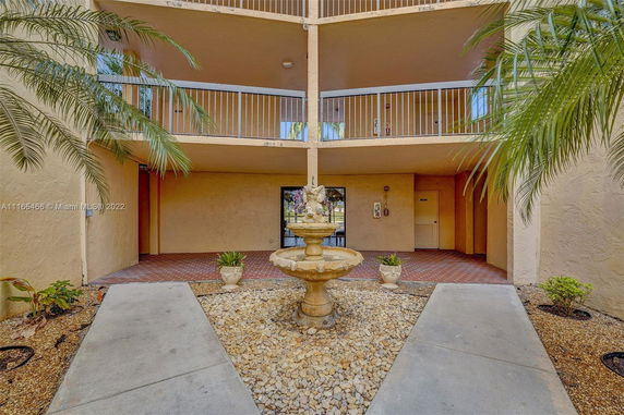 View of building with multiple floor balconies and a central courtyard fountain.