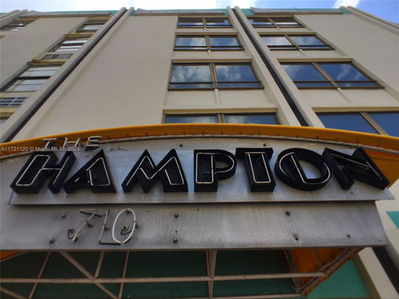 Front view of a multi-story building with large windows and a sign reading 'Hampton'.