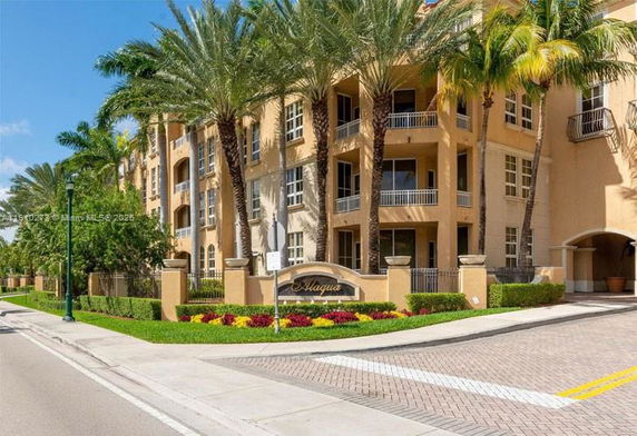Front view of a multi-story residential building with balconies and palm trees.