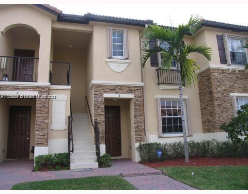 Front view of a two-story townhouse with a staircase and decorative stone facade.