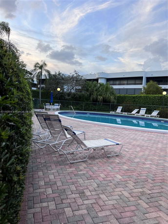 Outdoor swimming pool area with lounge chairs and surrounding greenery.