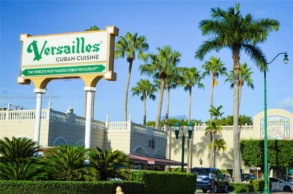 Front view of a restaurant with a large sign and palm trees.