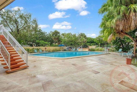 Outdoor swimming pool area with surrounding trees and lounge chairs.