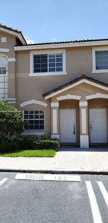 Front view of a townhouse with two entrances and a parking area.