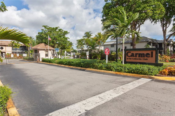 Front view of a residential community entrance with a security gate and signage.