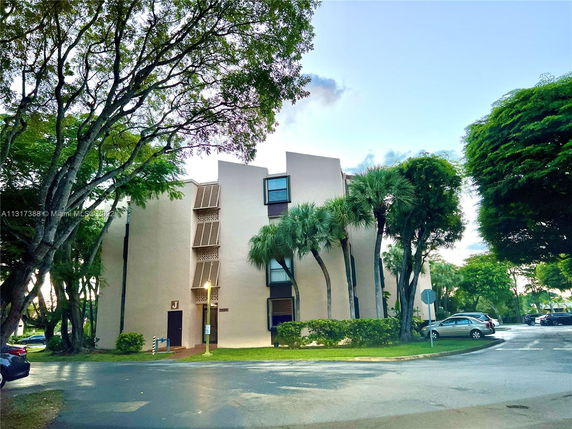 Front view of a multi-story residential building with surrounding trees.