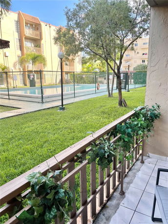View of an outdoor swimming pool area with a fence and nearby building.