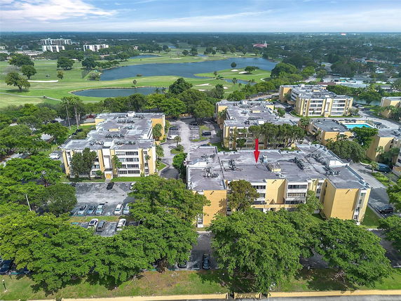 Aerial view of a residential complex with multiple buildings surrounded by greenery and water bodies.