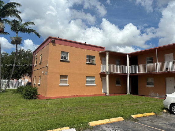 Exterior view of a two-story building with orange walls and white railings.