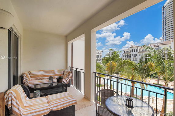 View from a balcony overlooking a swimming pool and nearby buildings.