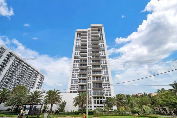 Front view of a tall residential building with multiple balconies.