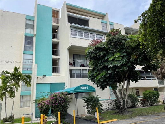 Front view of a multi-story apartment building with balconies and teal accents.