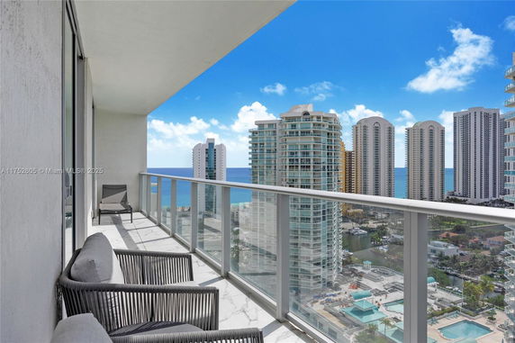 Balcony view from a high-rise building with ocean and nearby skyscrapers.