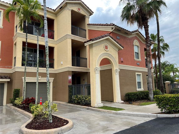 Front view of a multi-story residential building with balconies and arch details.