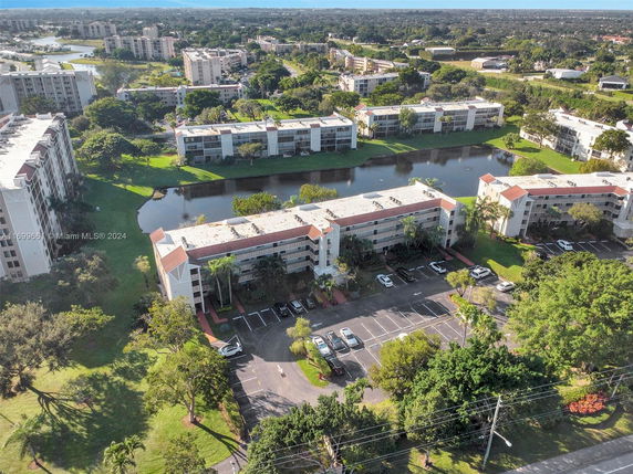 Aerial view of multiple apartment buildings and green landscape with parking areas.