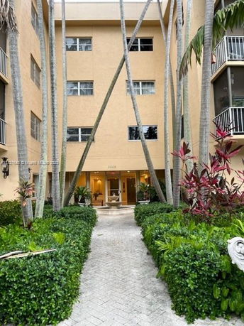 Front view of a multi-story building with balconies and entrance path.