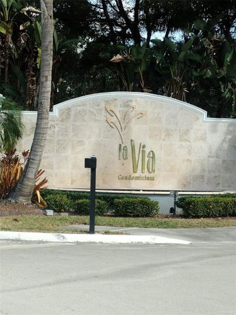 Entrance sign for La Via Condominium with surrounding greenery.