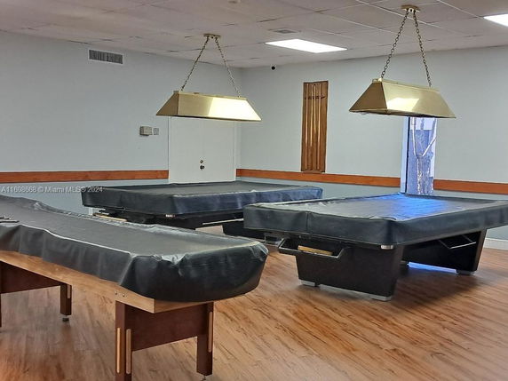 Room with billiards tables and hanging lights.