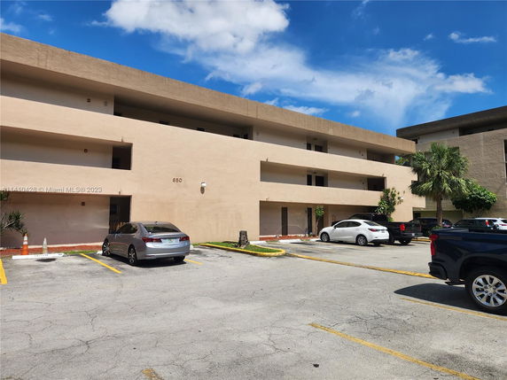 Outdoor parking area in front of a three-story building.