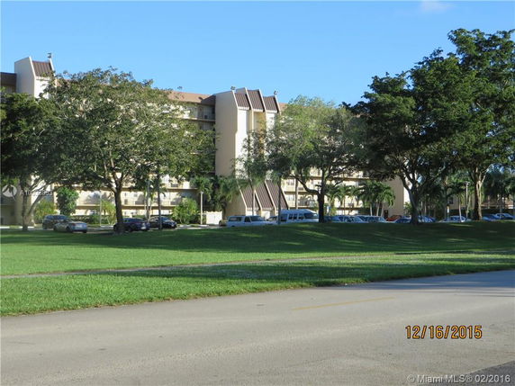 Multi-story residential building viewed from across a grassy area.
