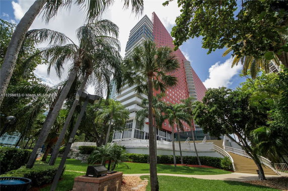 View of a high-rise building surrounded by palm trees and greenery.