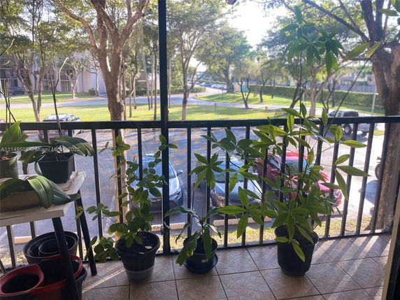 View from a balcony showing a parking area and trees.