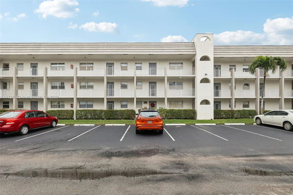 Front view of a multi-story building with a parking area in front.