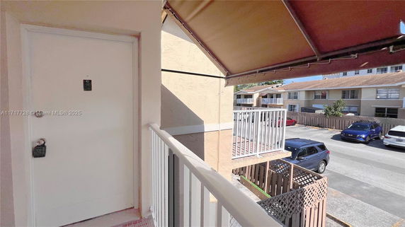 View from a balcony with nearby residential buildings and parked cars.