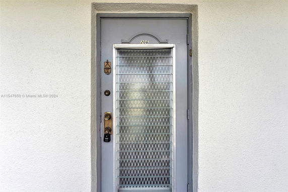 Front view of a gray door with a metal grill and numeric address.