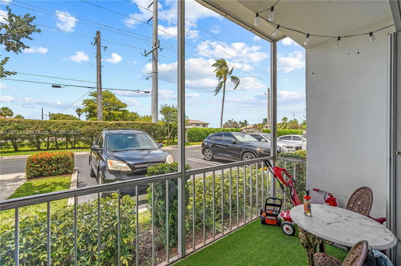 View of a parking area with parked cars and a small patio area with table and chairs.