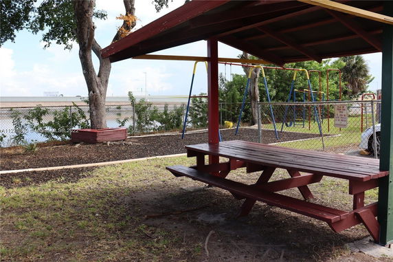 Outdoor play area with swings and a picnic table under a shelter.