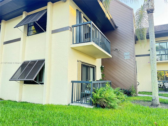 Front view of a two-story building with balconies and open window awnings.