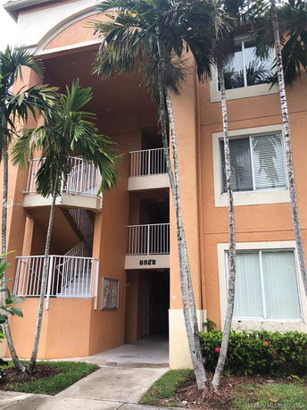 Front view of a multi-story apartment building with balconies and an entrance.