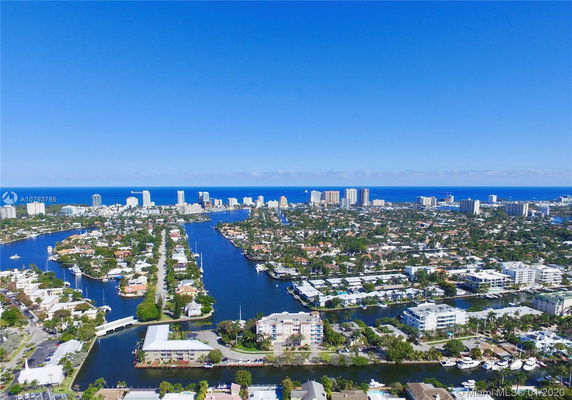 Panoramic aerial view of a coastal cityscape with waterways and high-rise buildings.