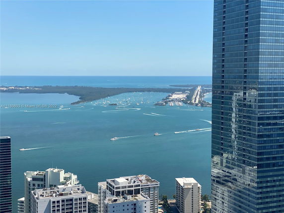 Panoramic view of city buildings and ocean with boats and islands in the background.
