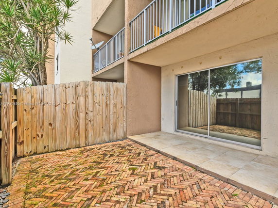 Outdoor view of a building with a fenced patio and sliding glass door.