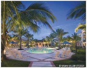 Outdoor swimming pool surrounded by palm trees and lounge chairs.